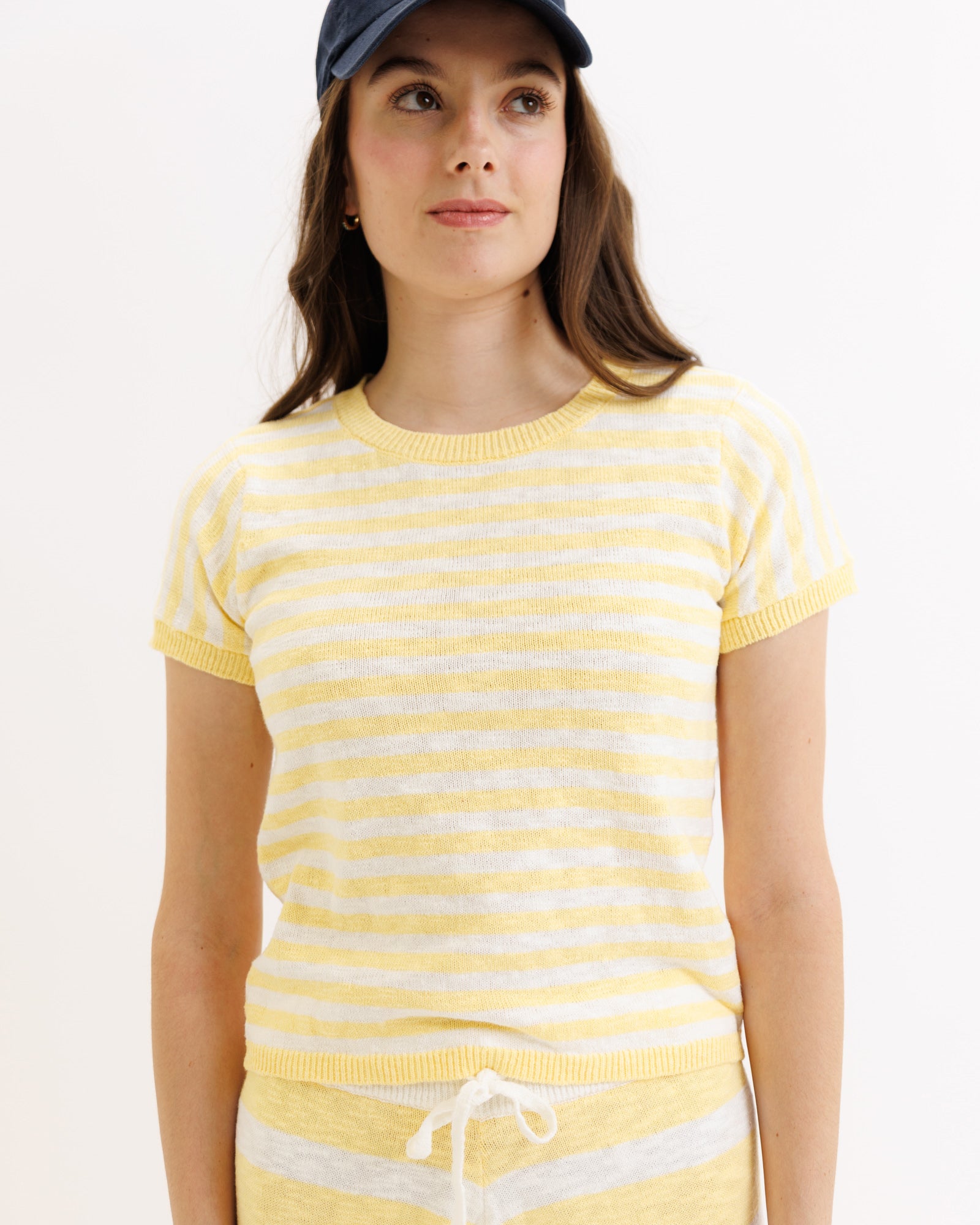 Woman wearing a yellow and white striped shirt with a plain background