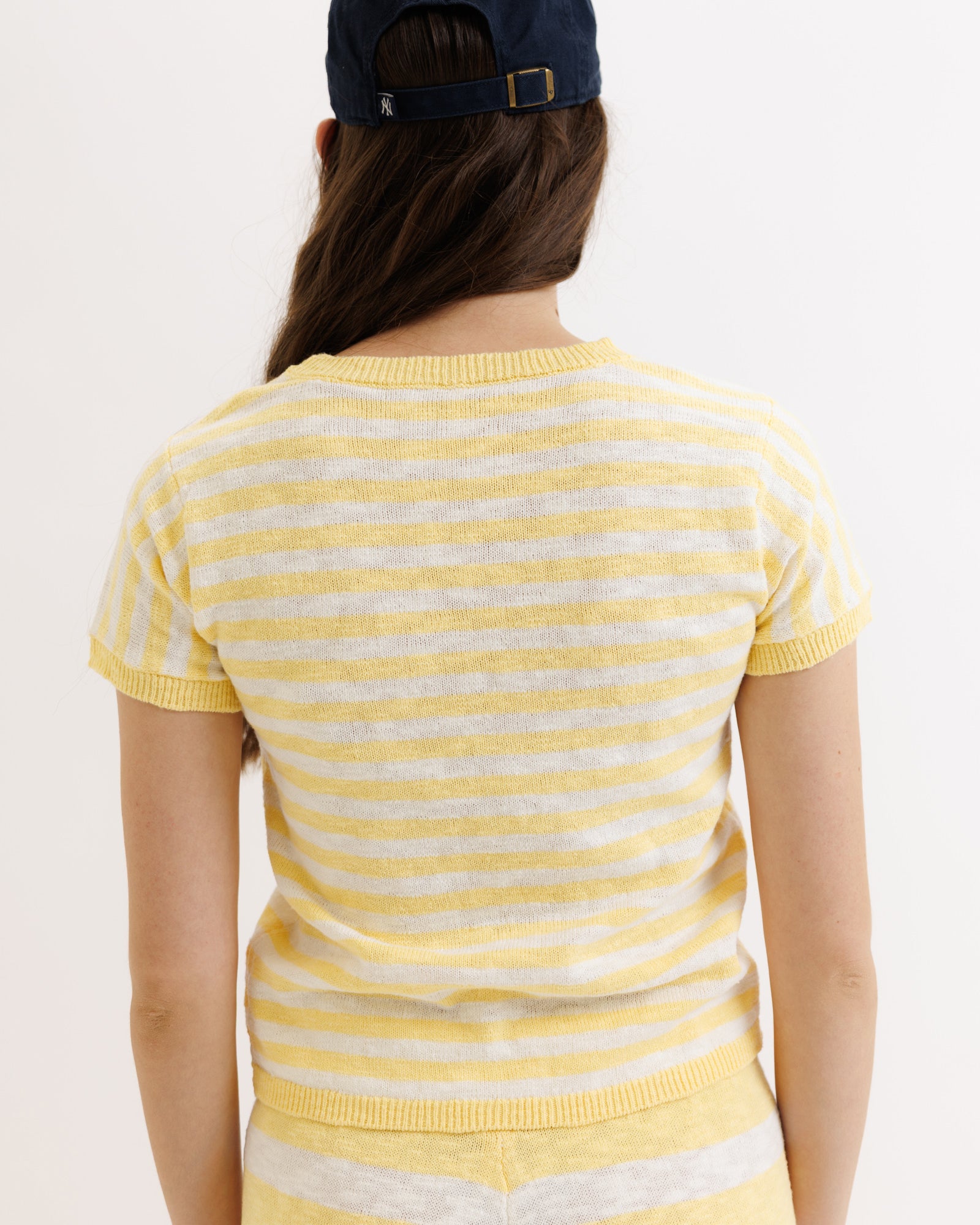 Person wearing a yellow and white striped sweater on a plain background