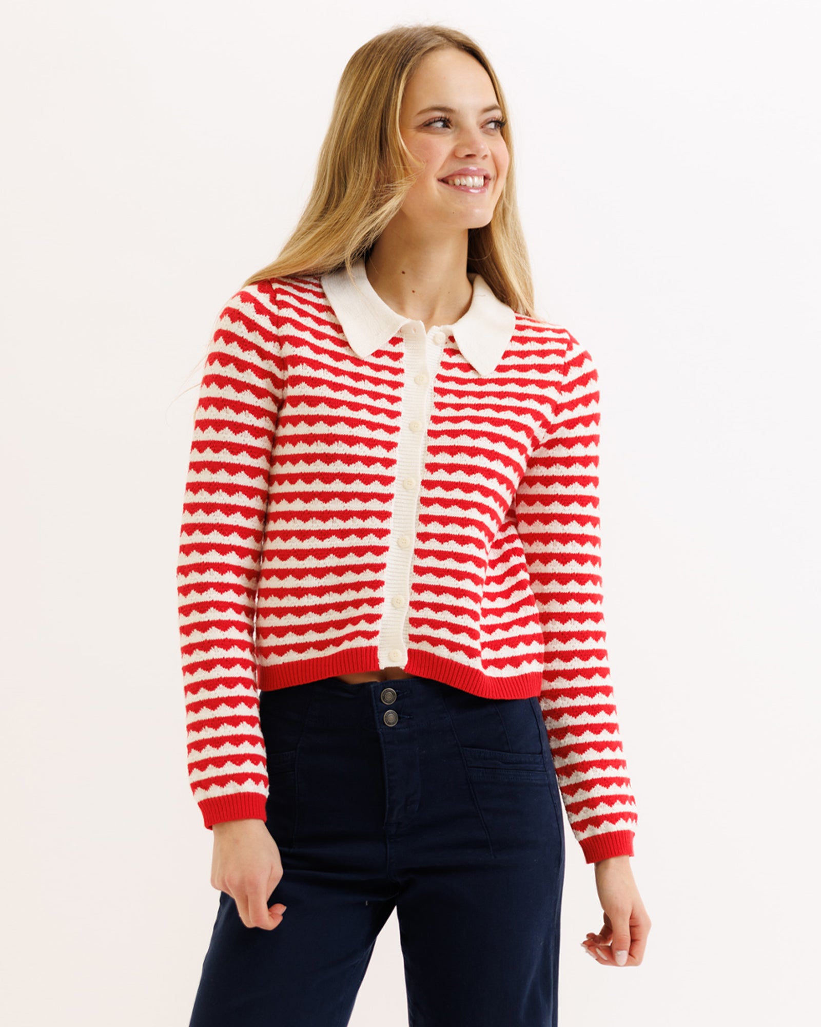 Woman wearing a red and white striped sweater with a white collar on a light background