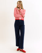 Woman wearing a red and white striped sweater and navy pants on a white background