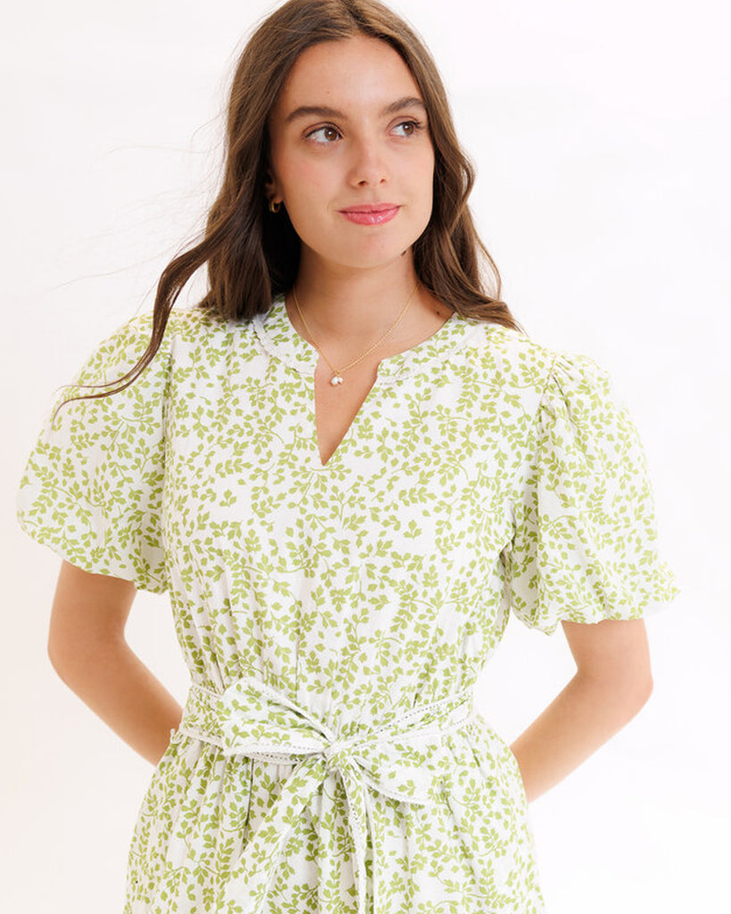 Model wearing a green printed short sleeve v-neck midi dress with a tie at the waist