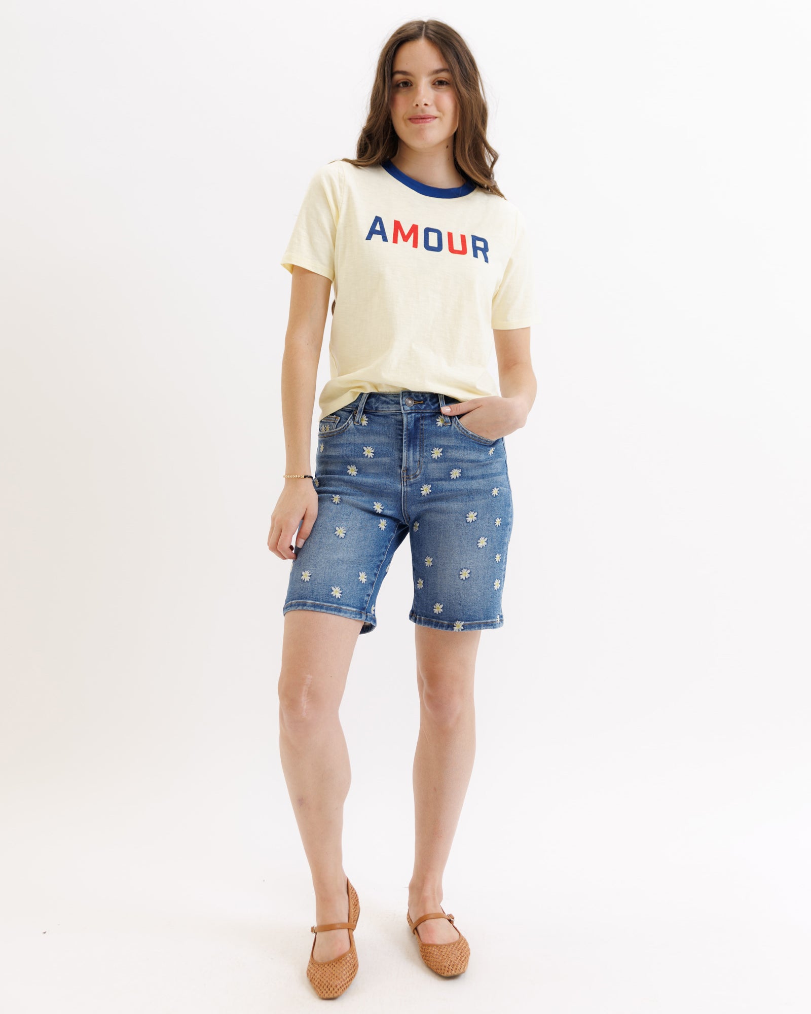 Woman wearing a 'AMOUR' t-shirt and denim shorts on a white background