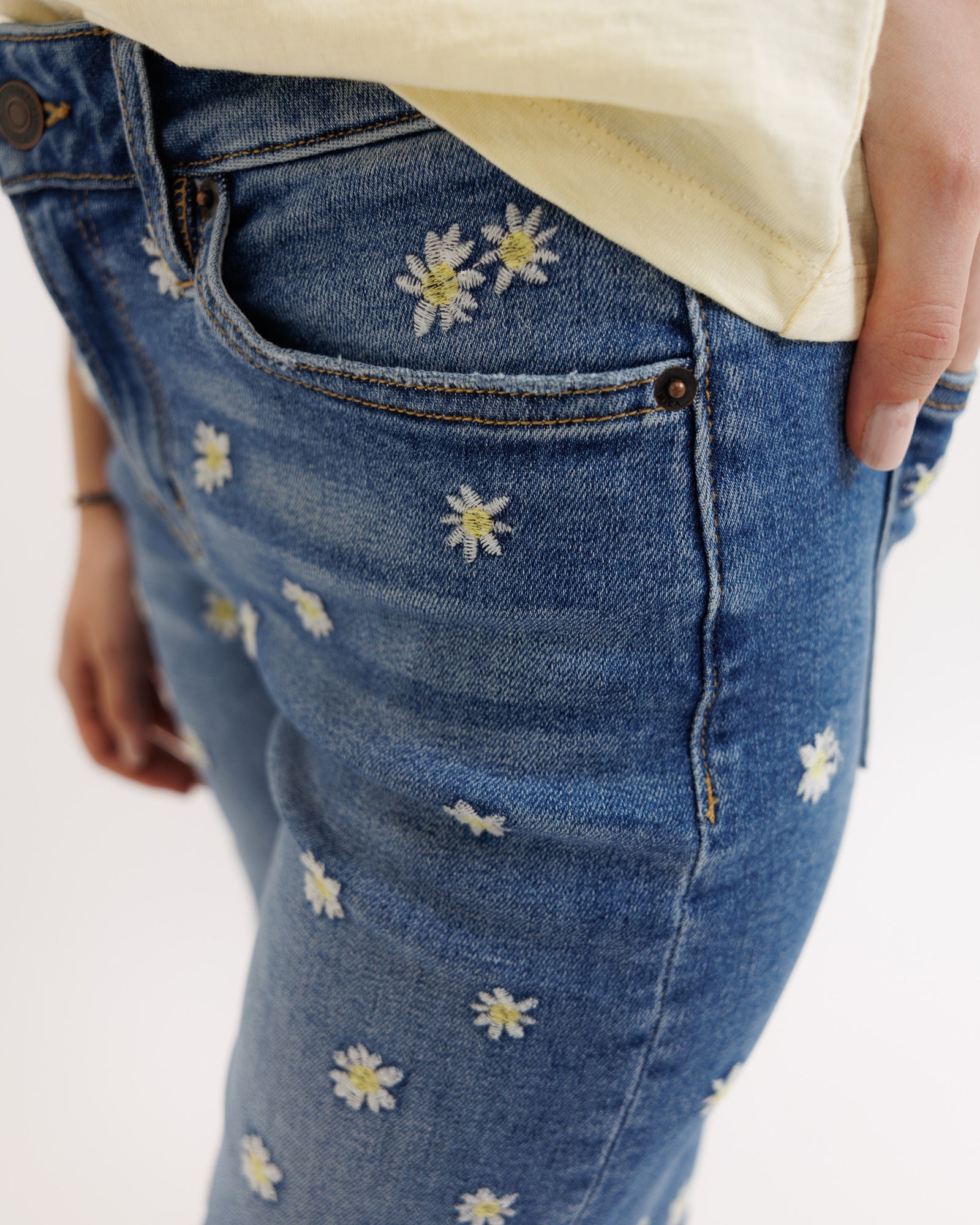 Blue jeans with floral embroidery on a white background