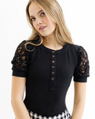 Woman wearing a black top with lace sleeves on a white background