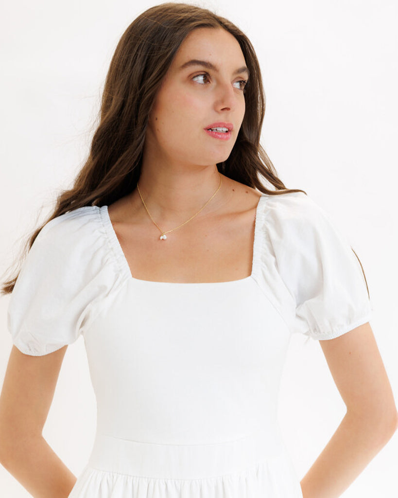 Model wearing a white with rainbow stripes on skirt, short sleeve, square neck, midi dress.