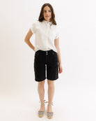 Woman wearing a white shirt and black shorts on a white background