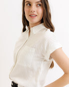 Woman wearing a white short-sleeve shirt on a plain background