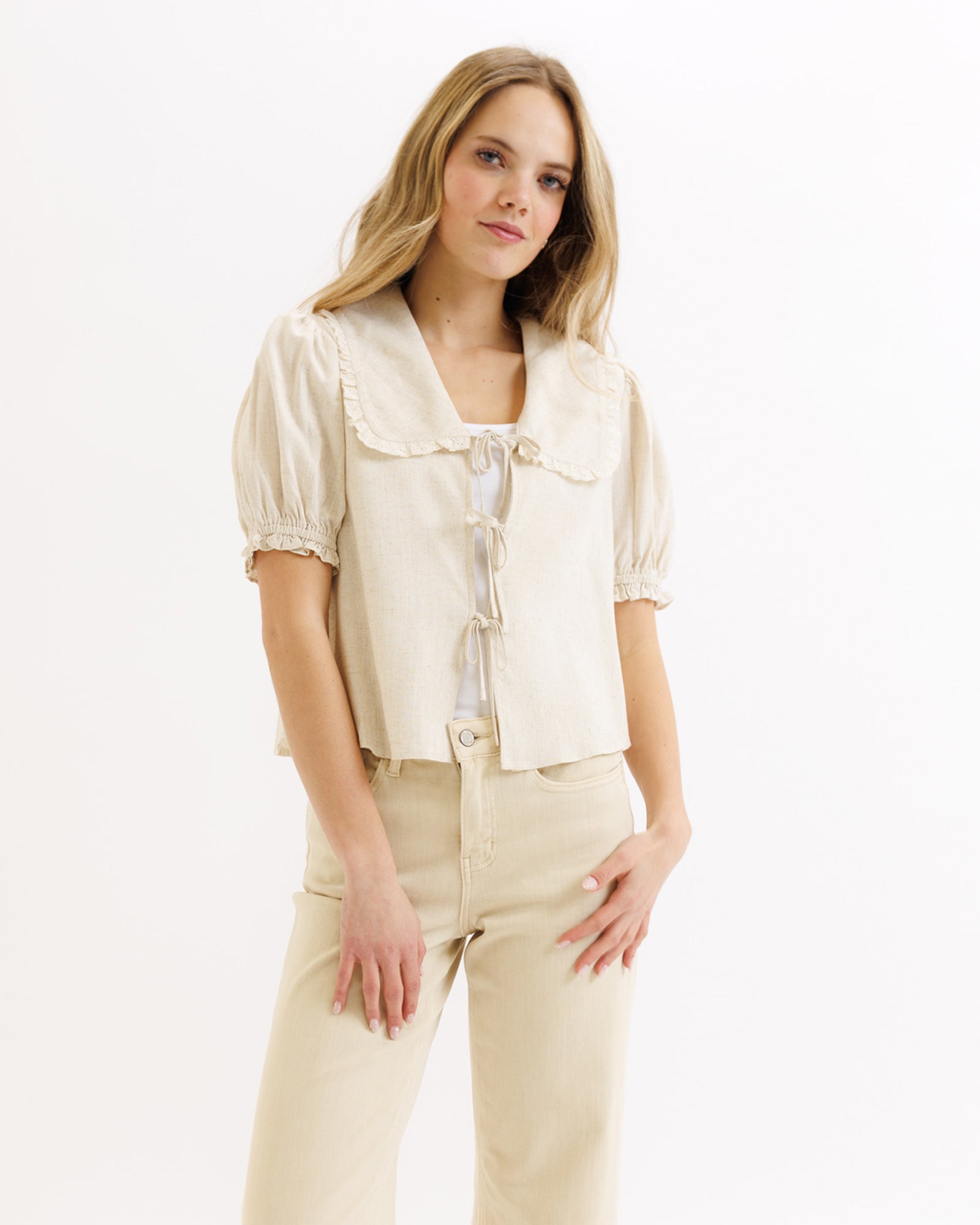 Woman wearing a beige blouse and pants on a white background