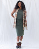 Full-length view of the olive green corduroy skirt styled with a tucked-in matching tank, plaid blanket scarf, and duck boots.