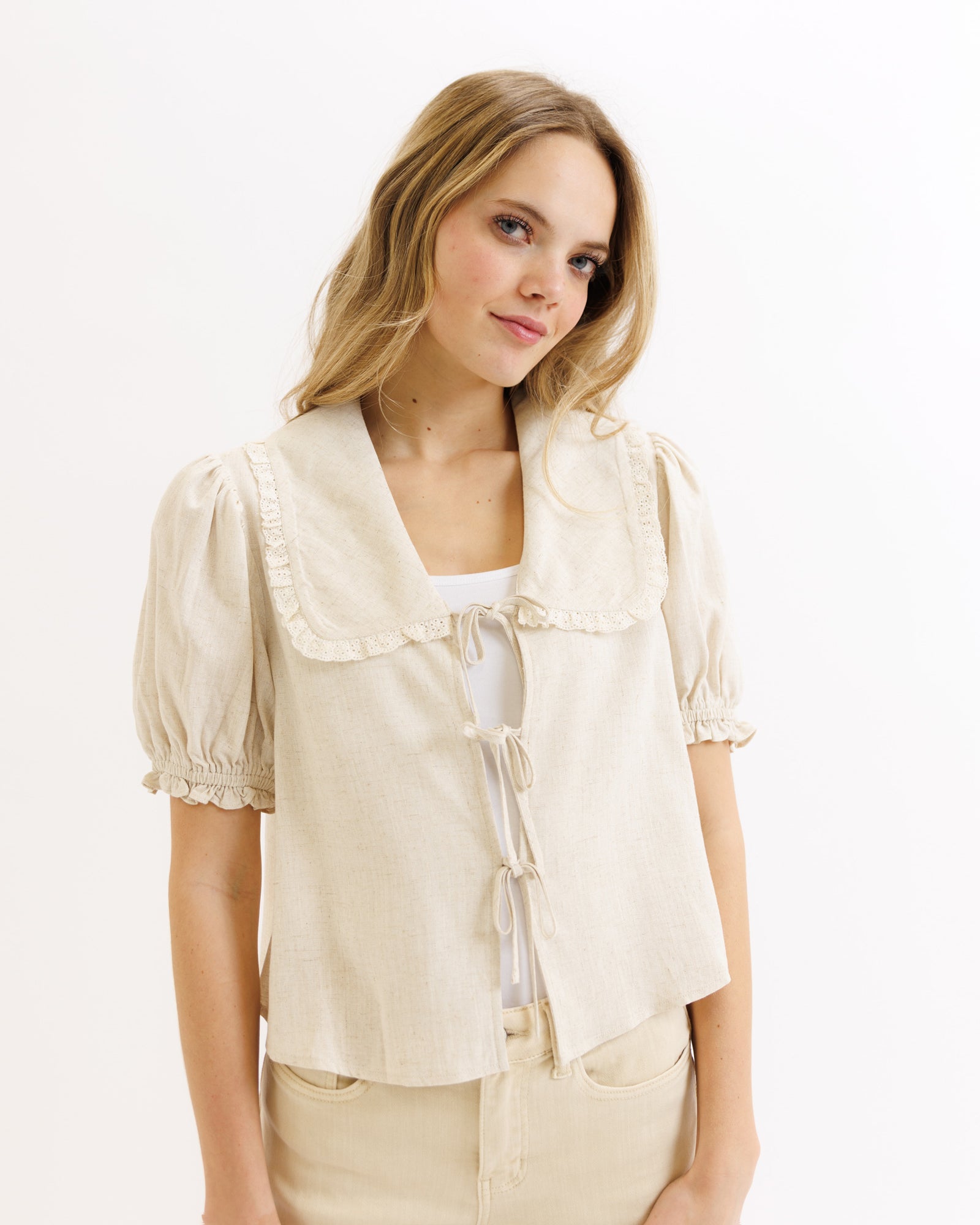 Woman wearing a light beige blouse with puff sleeves on a white background