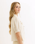 Woman wearing a beige blouse against a white background