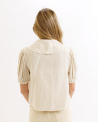 Woman wearing a beige blouse with short sleeves on a white background