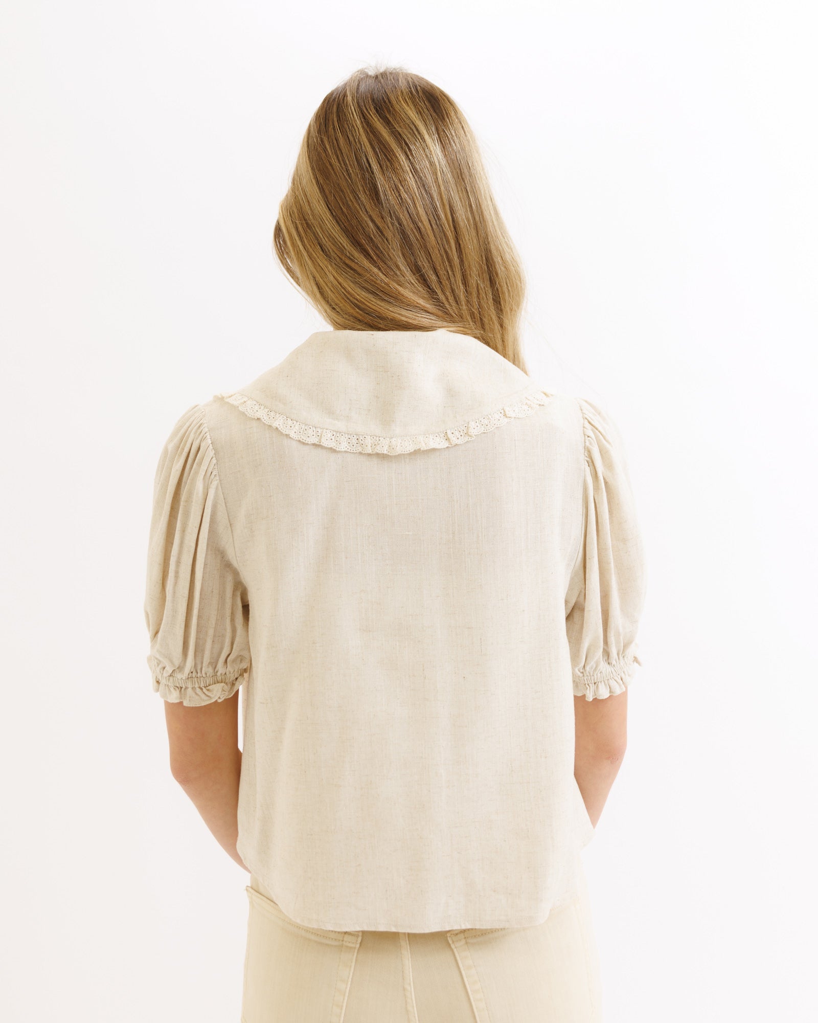Woman wearing a beige blouse with short sleeves on a white background