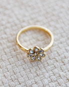 Gold ring with a floral design on a textured beige surface