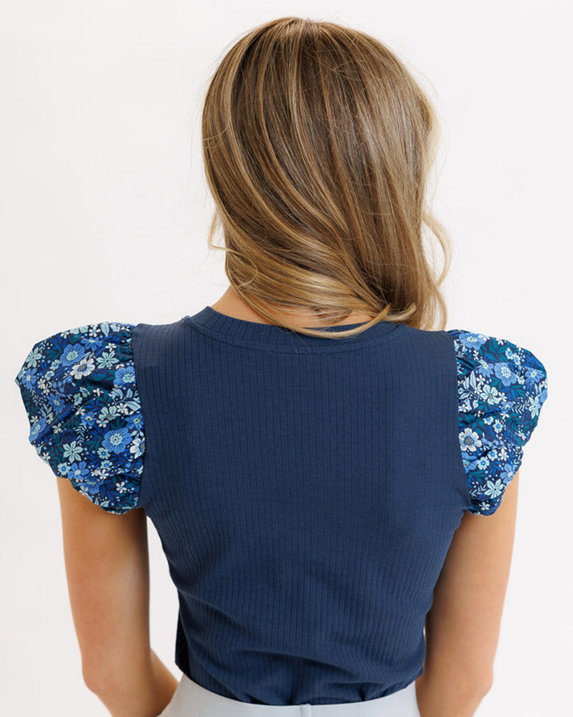 Model wearing a blue short sleeve knit tee with blue floral print puffed sleeves