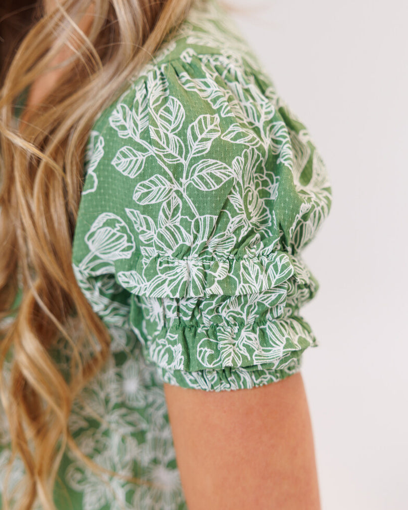 Model wearing a green floral print short sleeve v-neck blouse