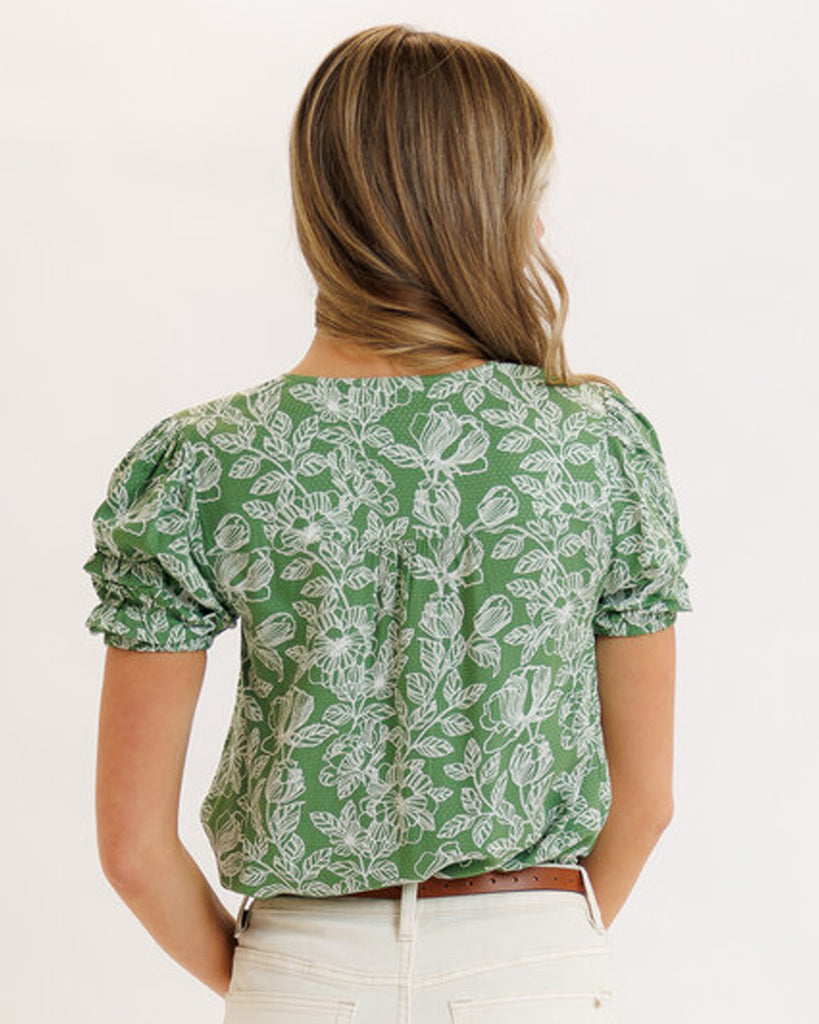 Model wearing a green floral print short sleeve v-neck blouse