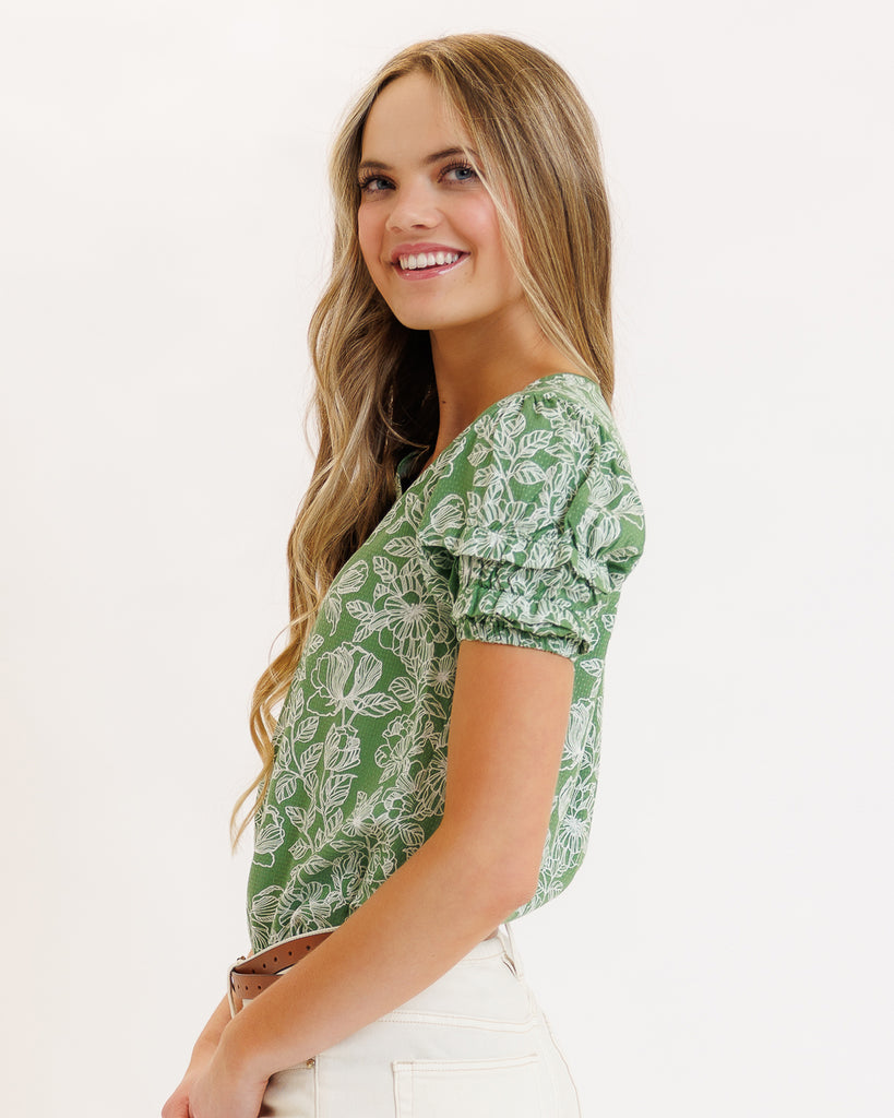 Model wearing a green floral print short sleeve v-neck blouse