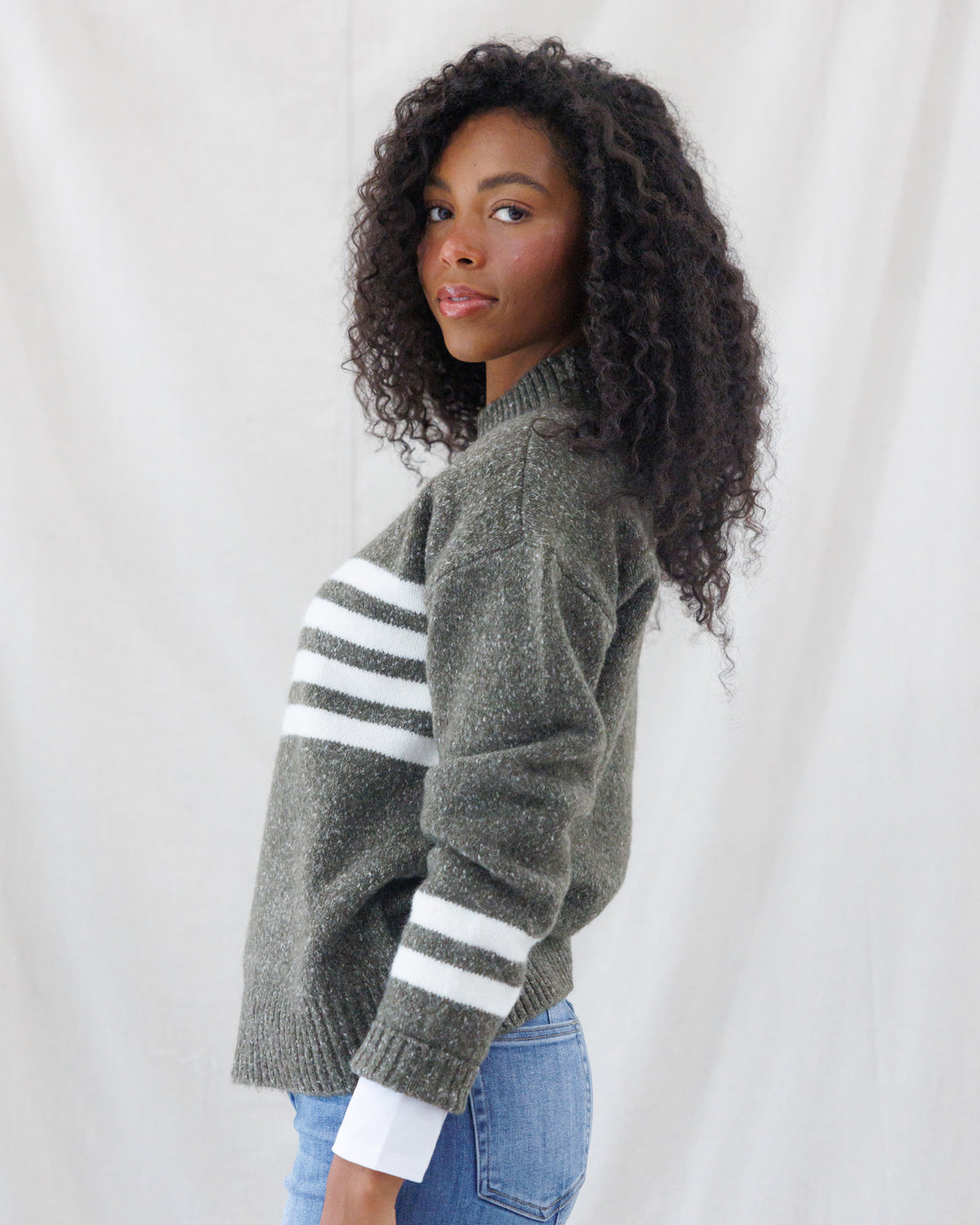Side profile showing the relaxed drop-shoulder silhouette, side hem coverage, and matching double white athletic stripes along the lower sleeves.