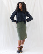 Model wearing the olive corduroy knee-length skirt styled with a dark button-up peasant blouse loosely tucked at the waist.