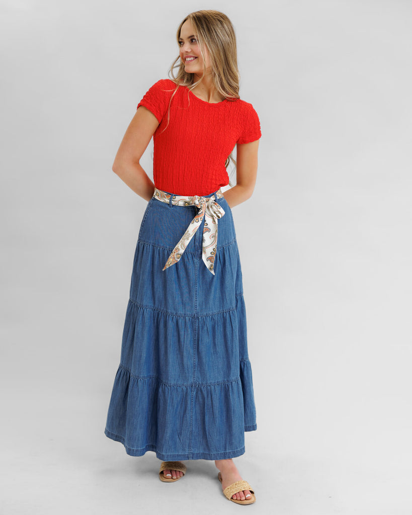 Model wearing a blue denim tiered maxi skirt with pockets.