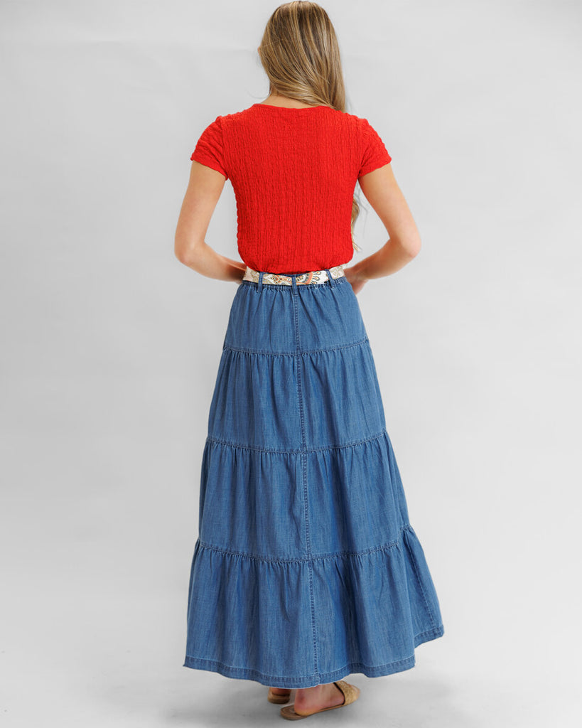 Model wearing a blue denim tiered maxi skirt with pockets.