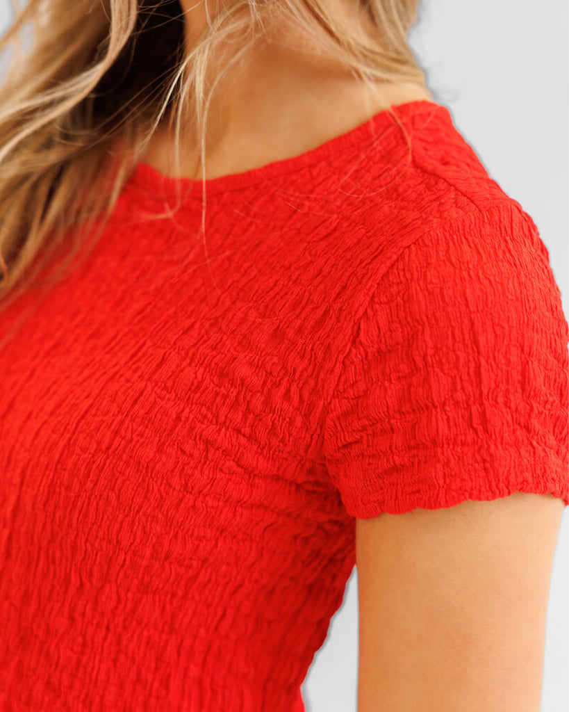 Model wearing a red textured short sleeve tee
