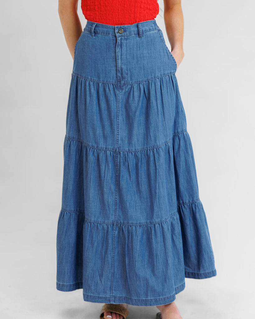 Model wearing a blue denim tiered maxi skirt with pockets.