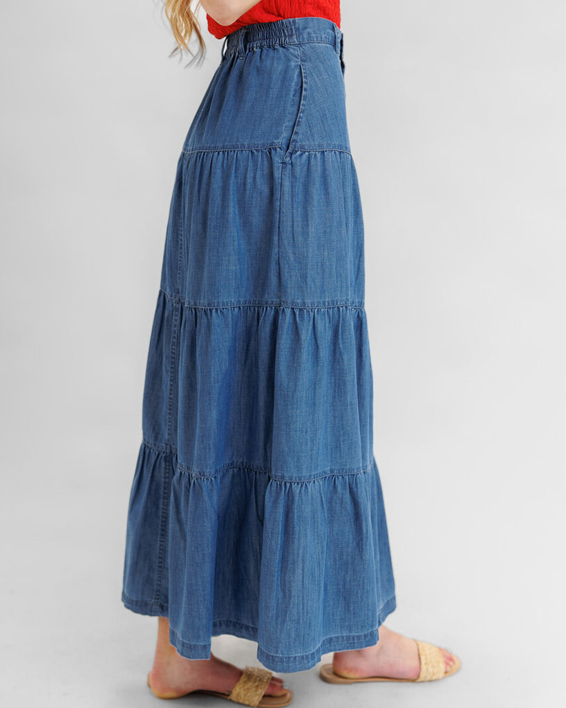 Model wearing a blue denim tiered maxi skirt with pockets.