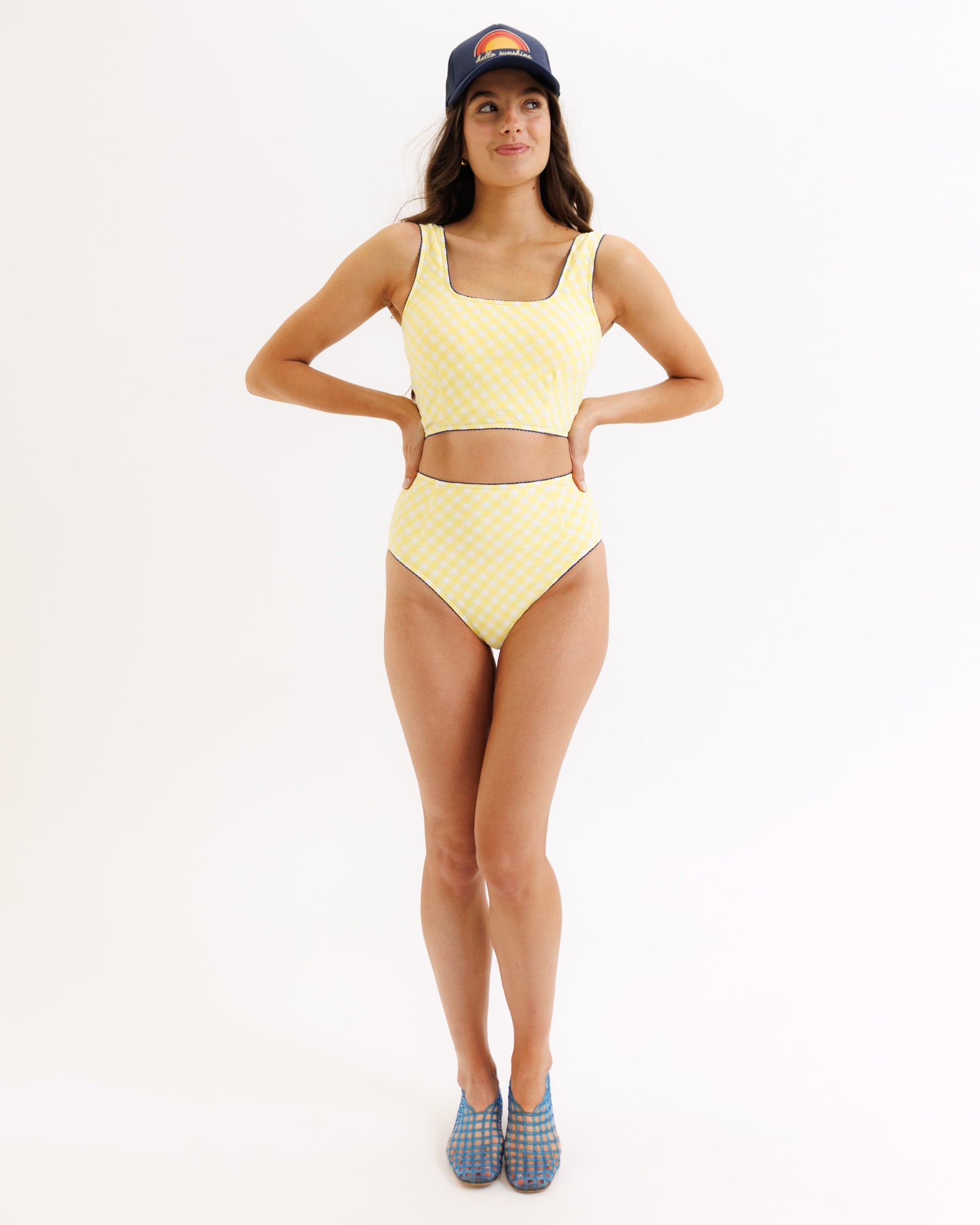 Woman wearing a yellow patterned swimsuit and blue cap on a white background