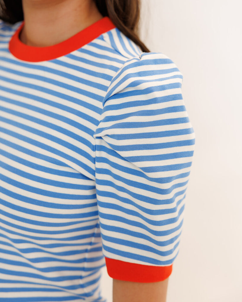 Model wearing a blue striped short sleeve tee with red trim around neckline and arms.