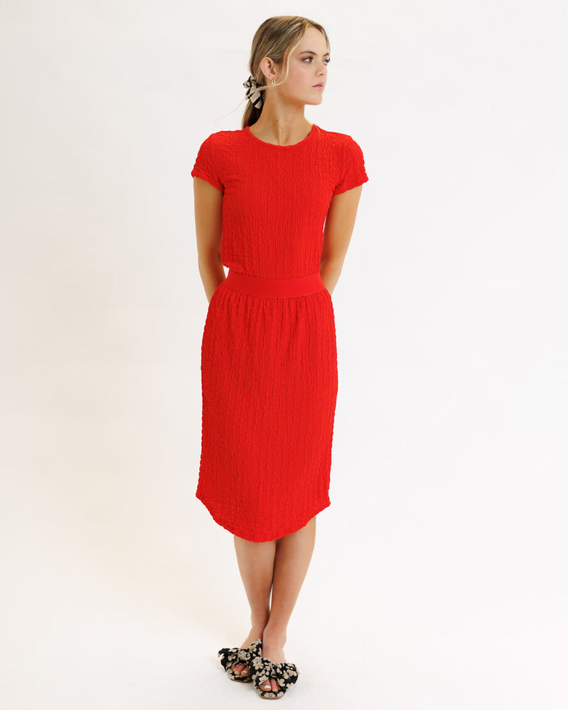 Model wearing a bright red textured midi length knit skirt.