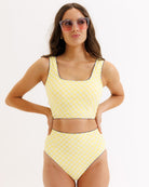Woman wearing a yellow polka dot bikini set on a white background