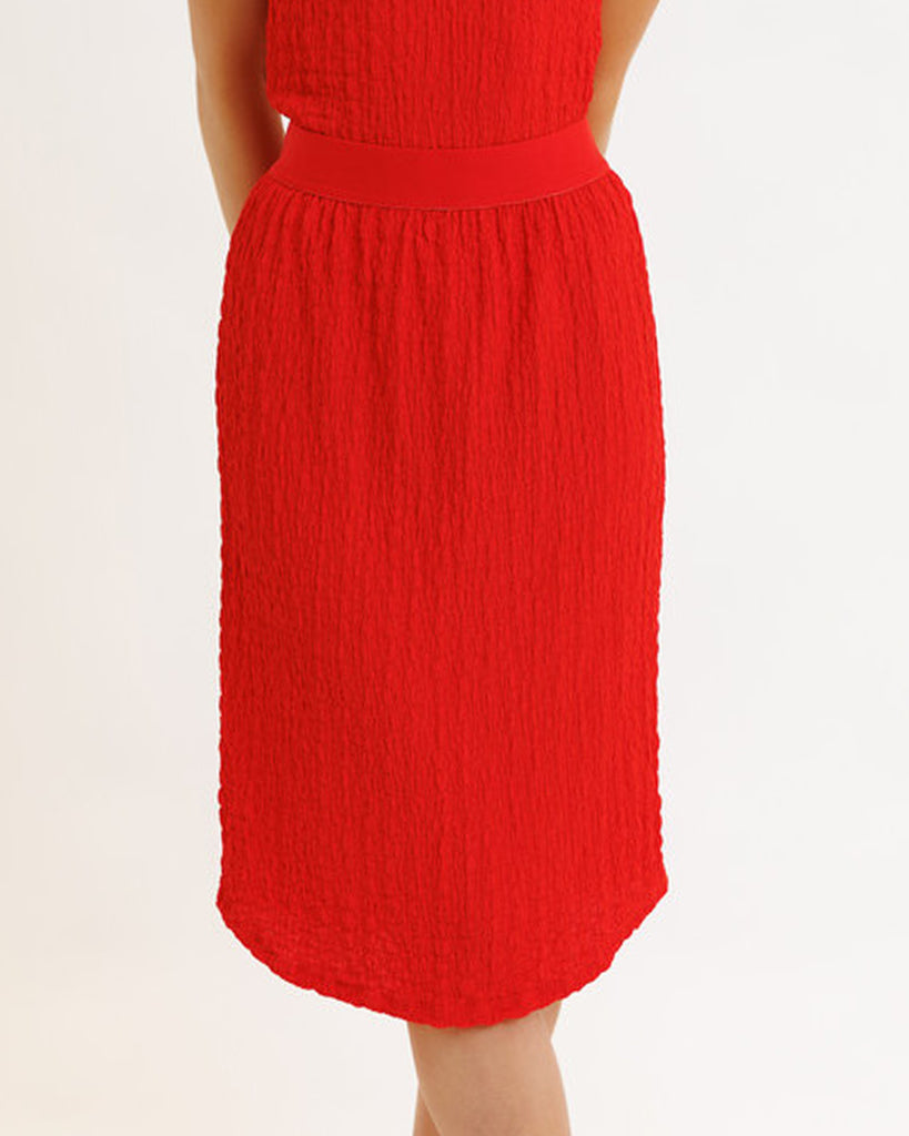 Model wearing a bright red textured midi length knit skirt.