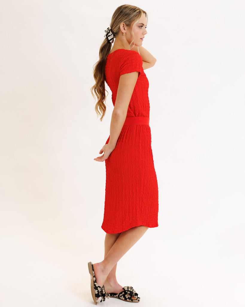 Model wearing a bright red textured midi length knit skirt.