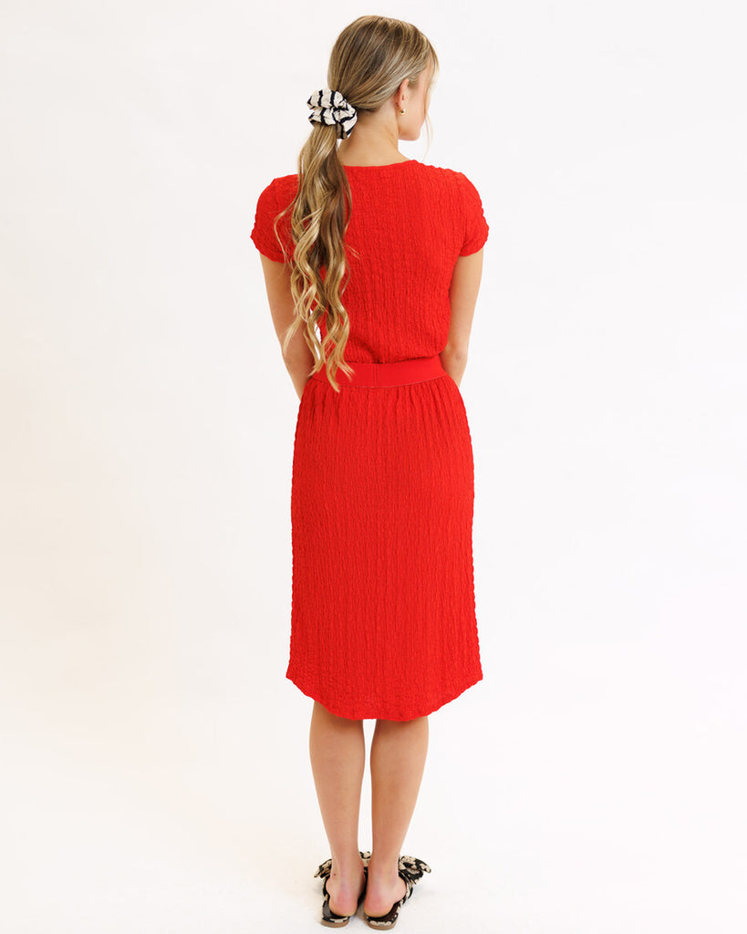 Model wearing a bright red textured midi length knit skirt.