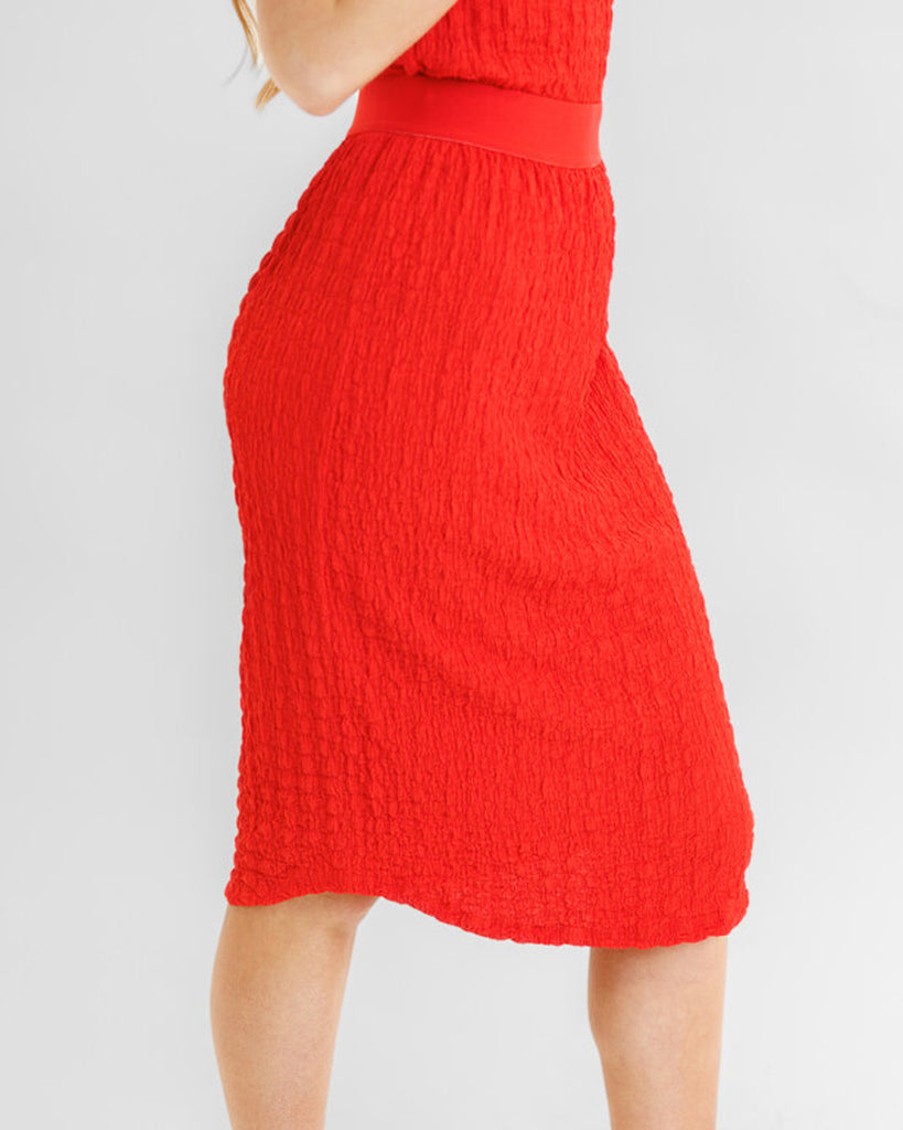 Model wearing a bright red textured midi length knit skirt.