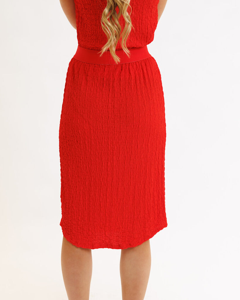 Model wearing a bright red textured midi length knit skirt.