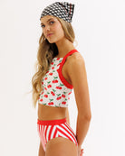Woman wearing a red and white patterned bikini with a matching headscarf on a white background