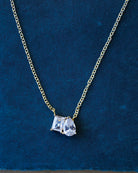 Gold necklace with a diamond pendant on a blue background