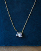 Gold necklace with a diamond pendant on a blue background
