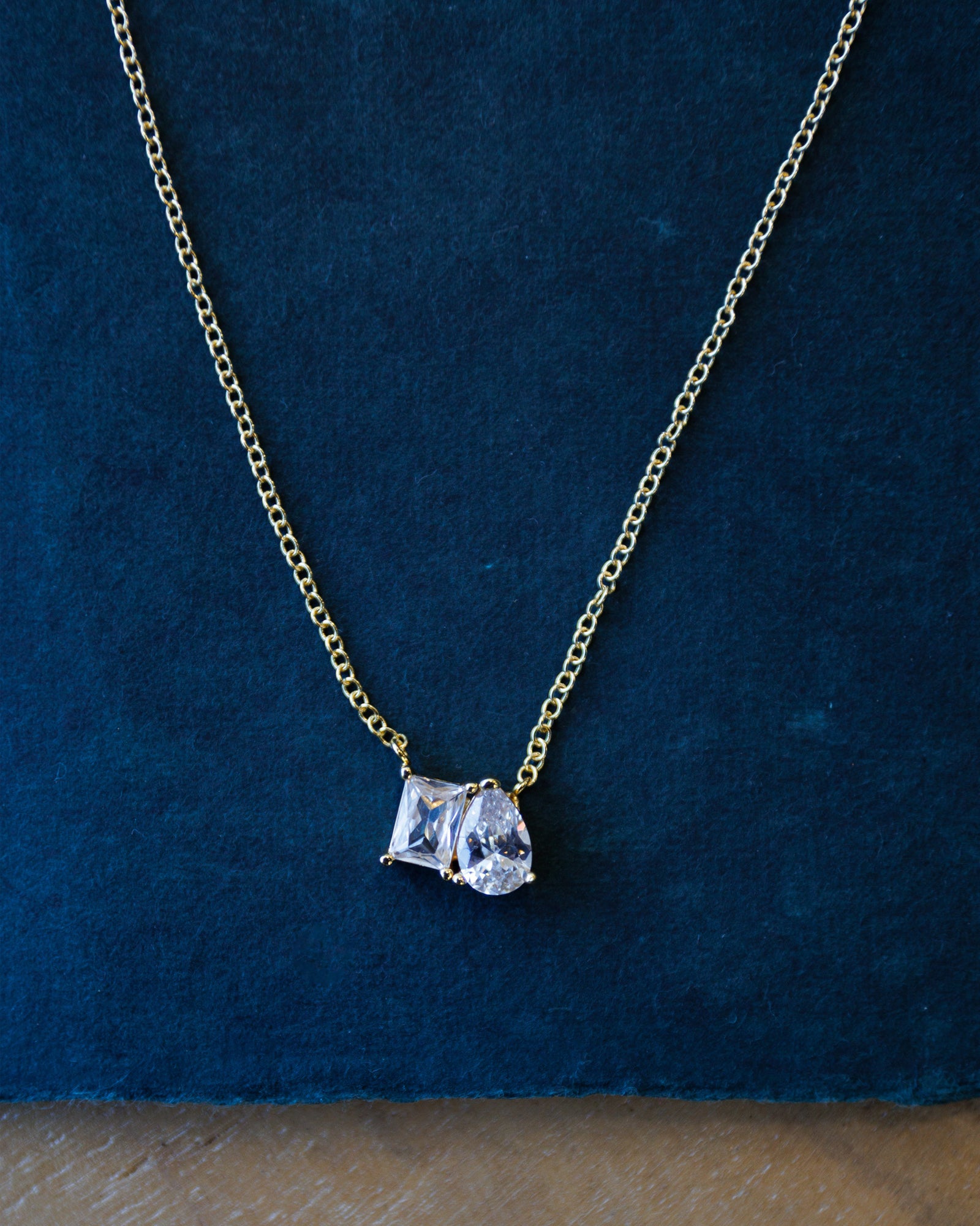 Gold necklace with a diamond pendant on a blue background