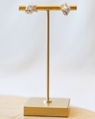 Gold earring stand with two crystal earrings on a light background
