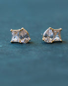 Pair of diamond-looking stud earrings on a dark blue background