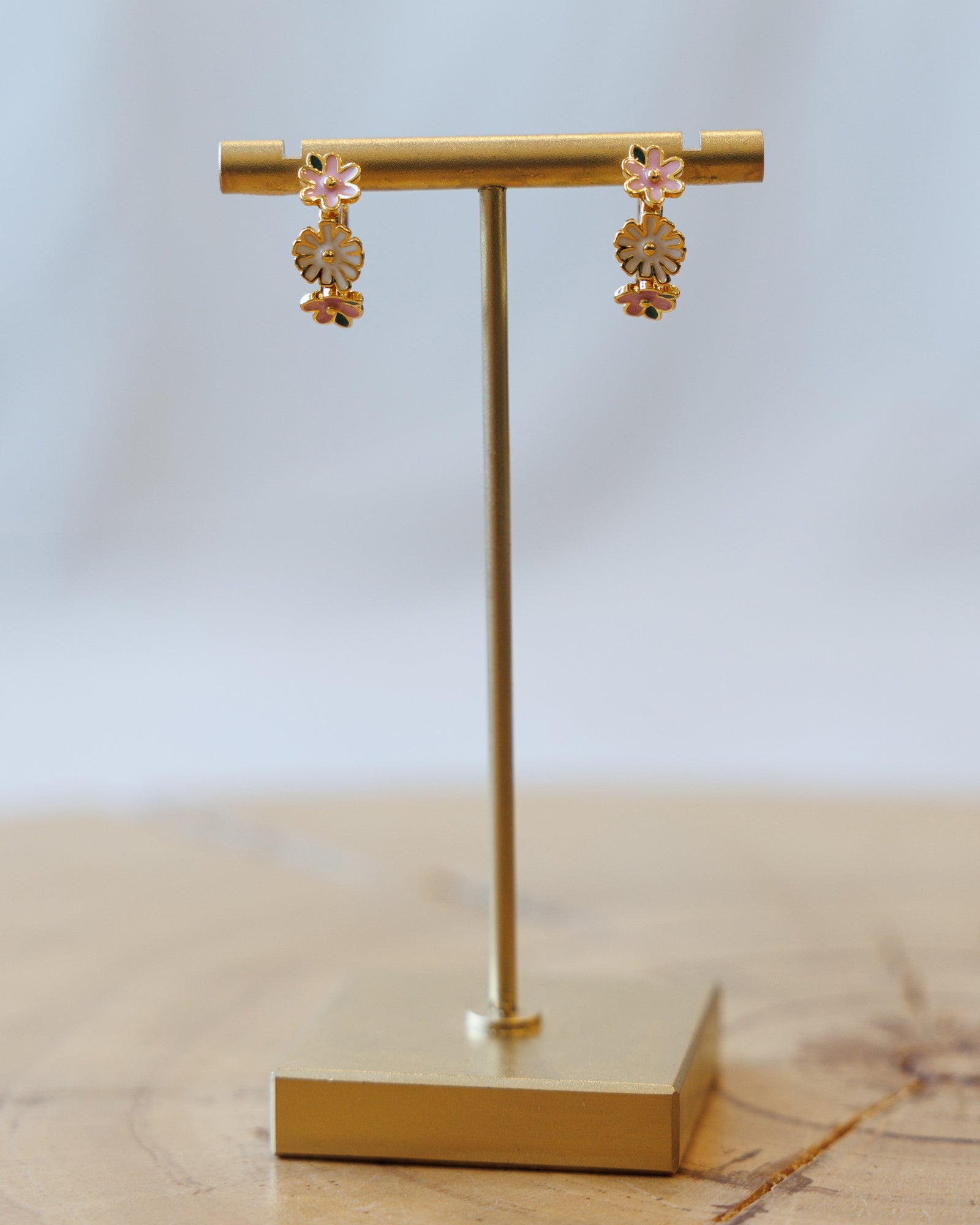 Gold earrings on a gold earring stand with a light background
