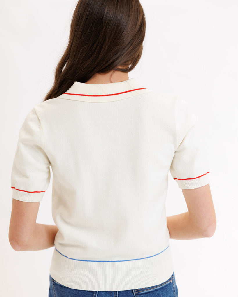 Model wearing a white short sleeve polo sweater