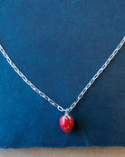 Necklace with a red strawberry-shaped pendant on a blue background
