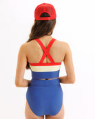 Person wearing a blue and red swimsuit with a red cap on a white background