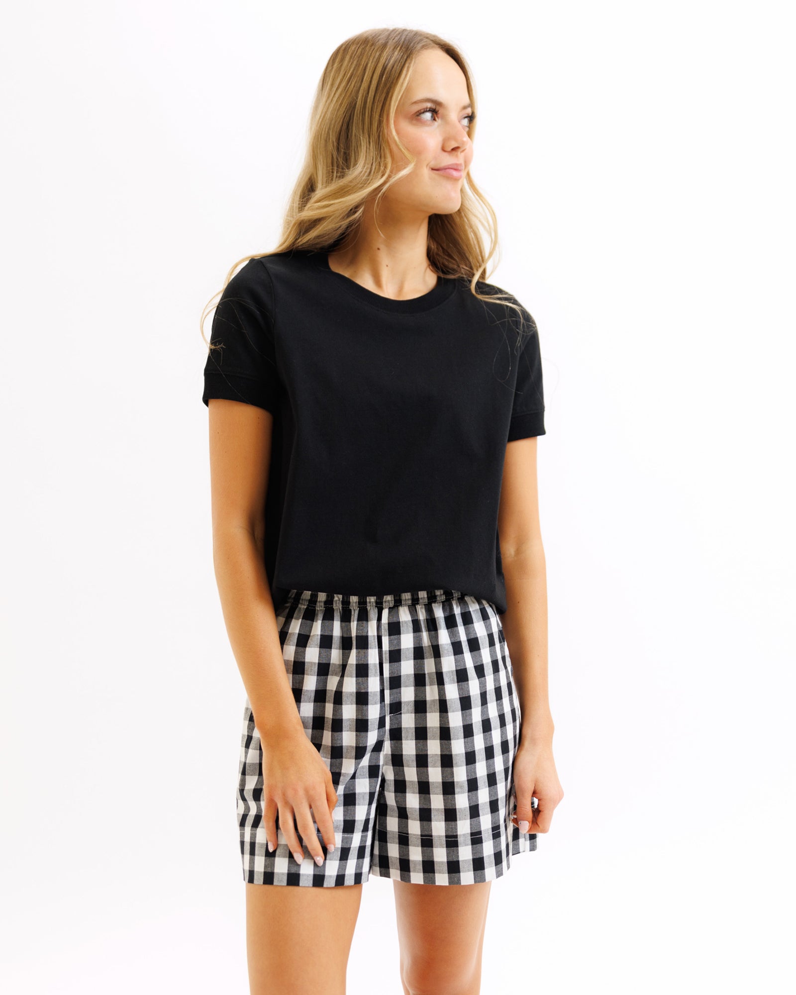 Woman wearing a black t-shirt and a black and white checkered skirt on a white background