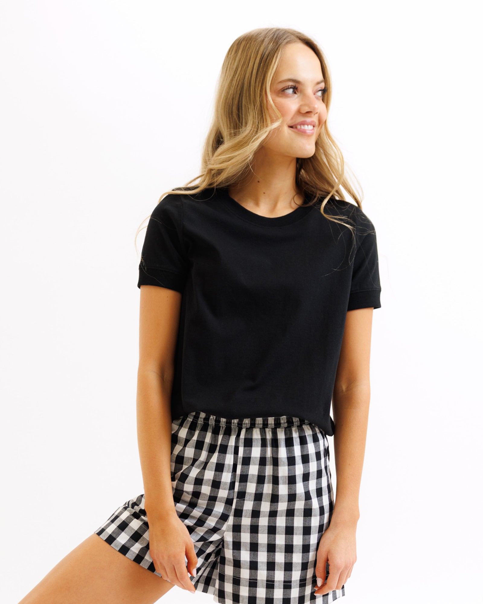 Woman wearing a black t-shirt and checkered shorts on a white background